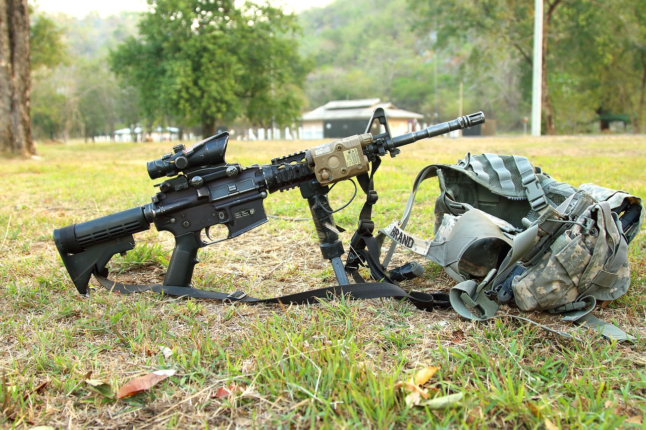 A rifle together with an army's backpack on the ground